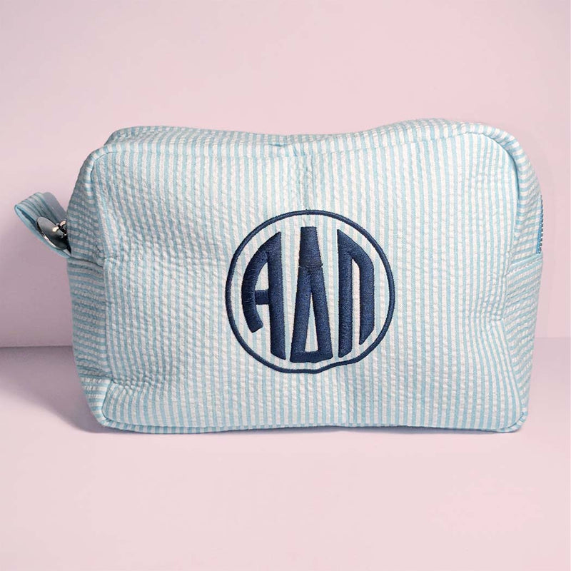 Light blue toiletry bag with monogram on a pink background