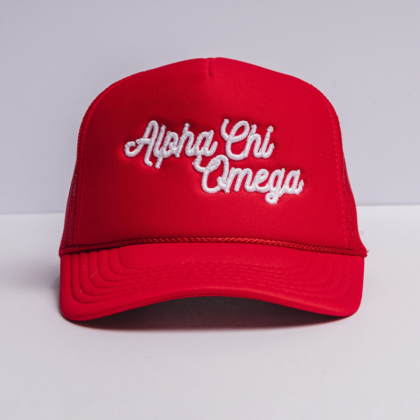 Red cap with 'Alpha Chi Omega' text on a light gray background