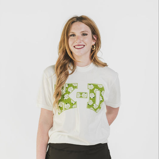 Woman wearing a white t-shirt with green graphics and a black skirt on a white background