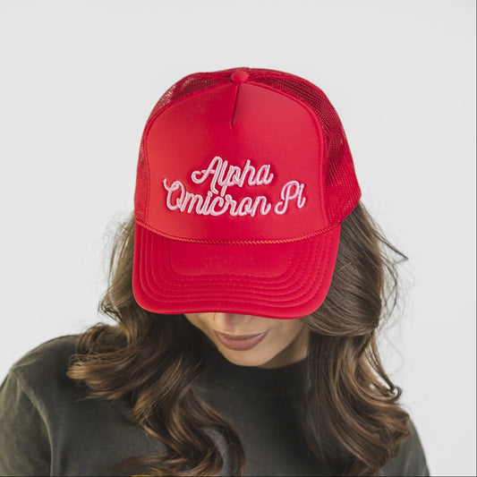 Person wearing a red cap with 'Alpha Omicron Pi' and a green t-shirt with 'Tri Delta' logo.