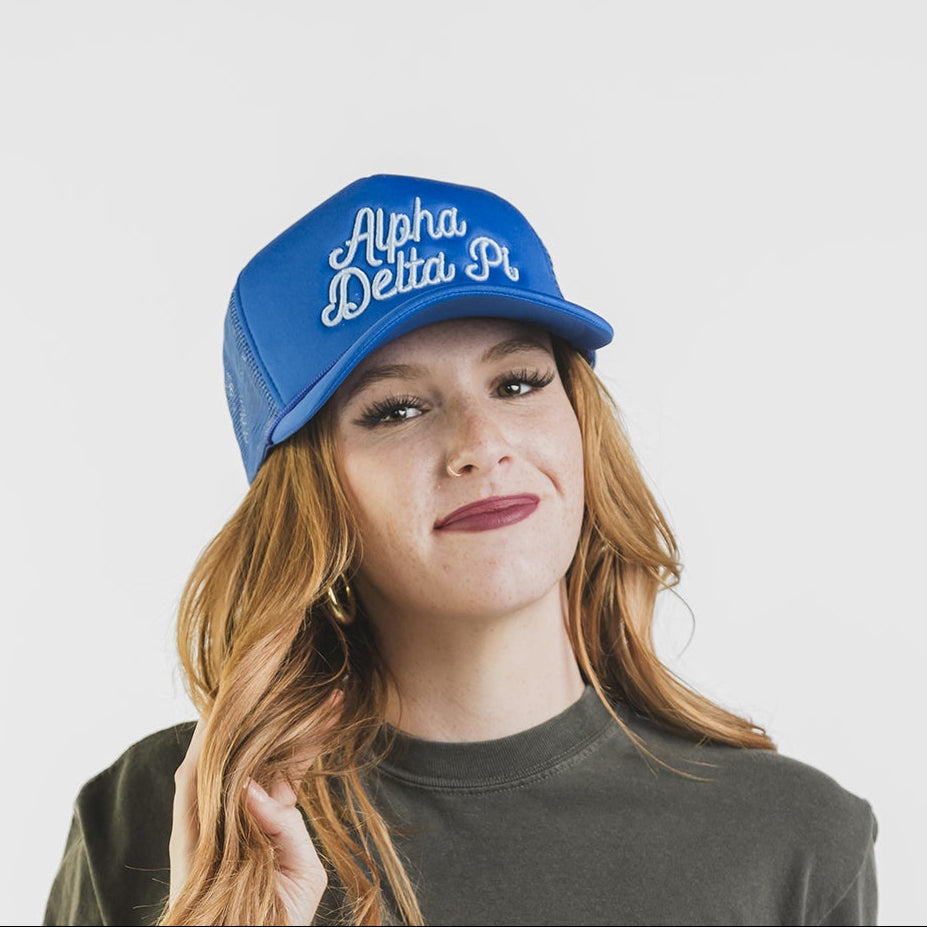 Person wearing a green t-shirt with a red logo and a blue cap with white text on a white background