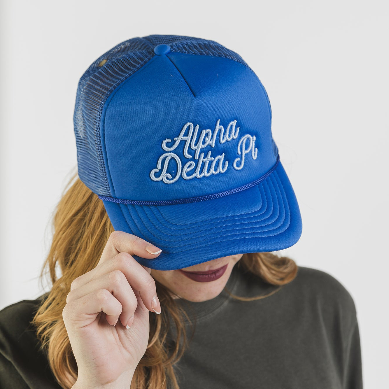 Person wearing a blue 'Alpha Delta Pi' cap with a plain background