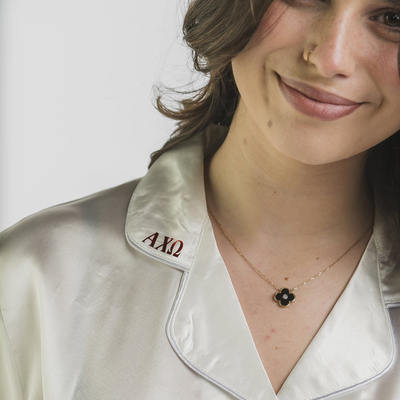 Woman wearing a satin shirt with a collar featuring 'Alpha Xi Delta' sorority letters.